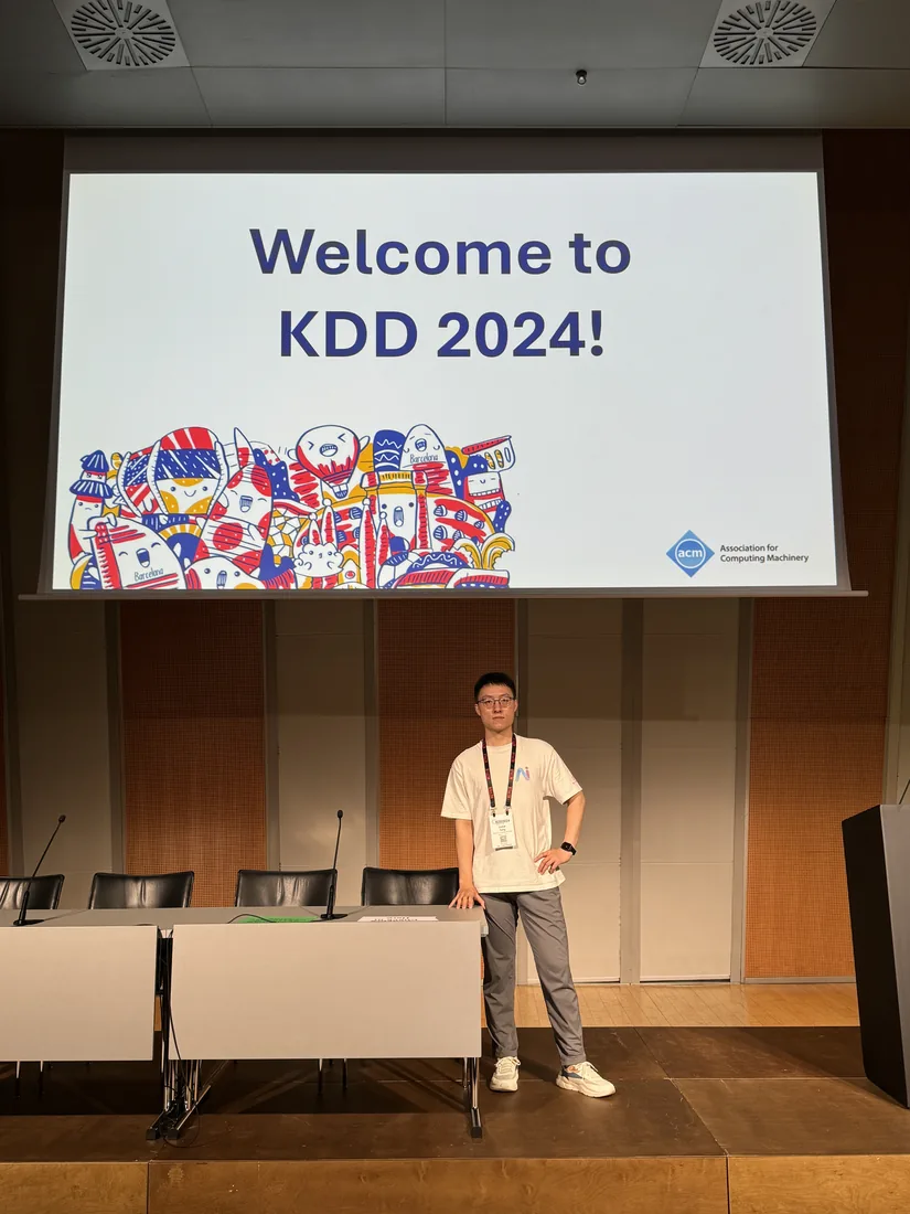 At the KDD 2024 conference venue beneath the welcome screen.