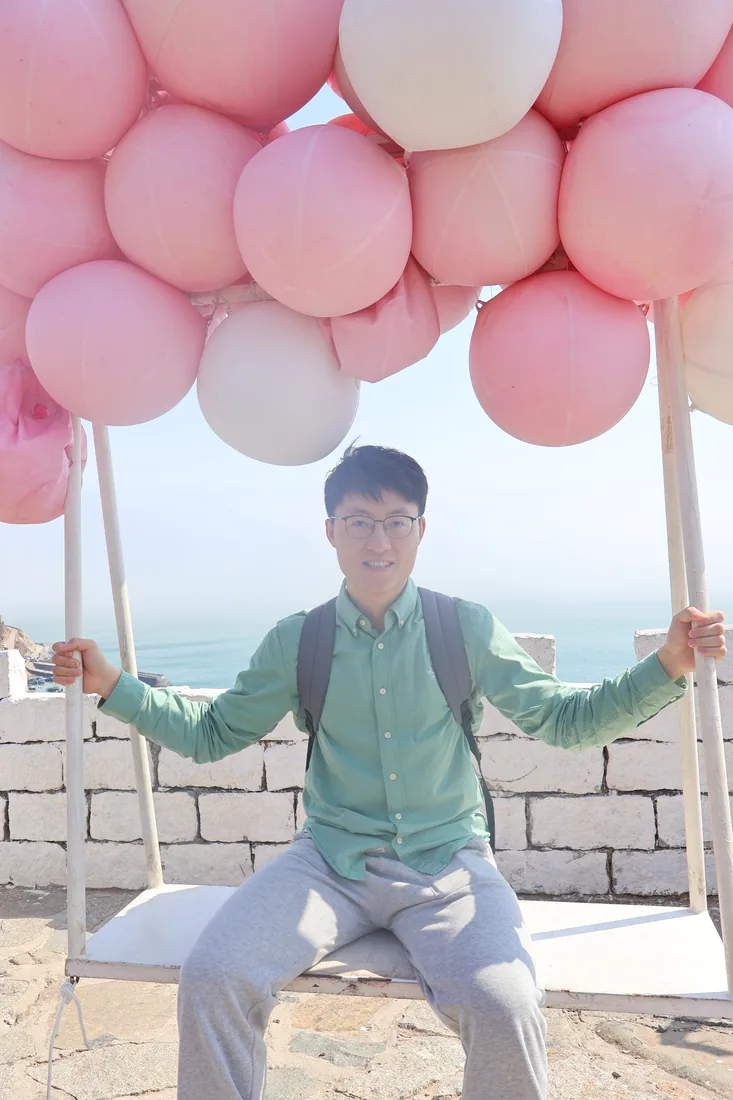 A seaside portrait beneath pink balloons.