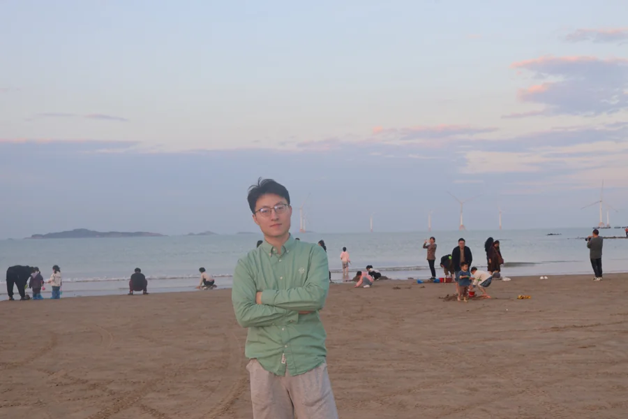 Standing on the beach in Pingtan with offshore wind turbines in the distance.